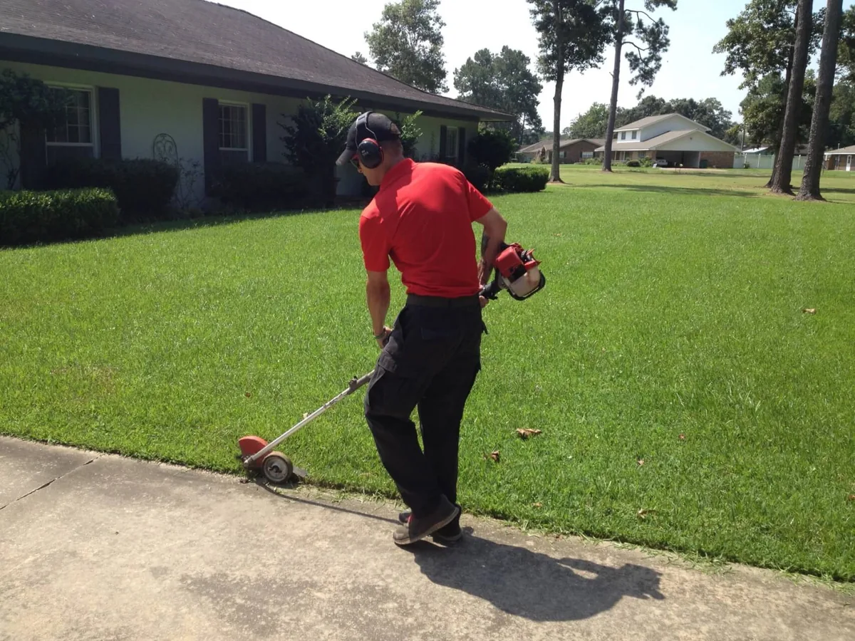 String trimming along a sidewalk during lawn maintenance